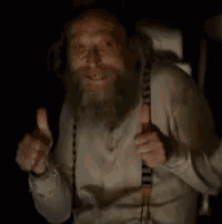 a man with a beard is giving a thumbs up in the dark