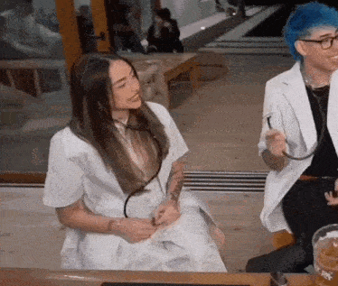 a man and a woman are sitting at a table with a stethoscope around their neck .