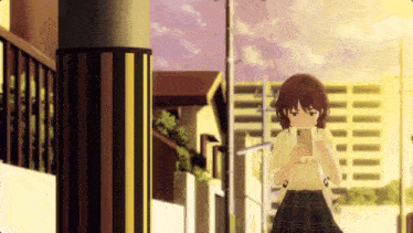 a girl in a plaid skirt is looking at her phone while walking down a street .