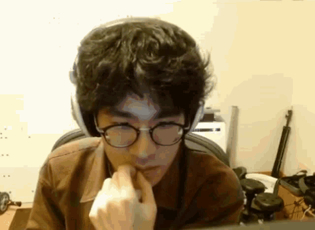 a young man wearing glasses and headphones is sitting in front of a computer .