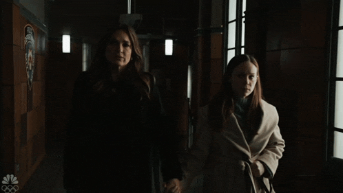 two women holding hands in front of a window with a nbc logo on the bottom