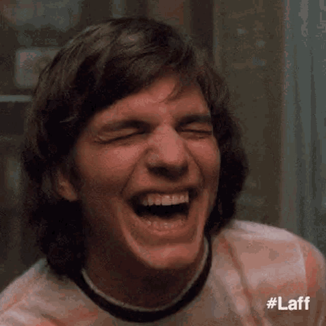 a close up of a man laughing with his mouth open .