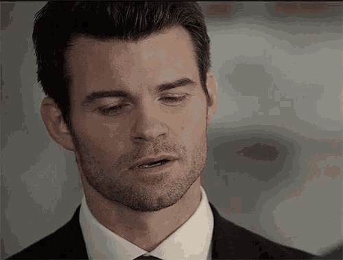 a close up of a man 's face with a beard wearing a suit and tie
