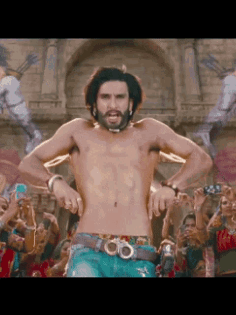 a shirtless man with a beard is dancing in front of a crowd