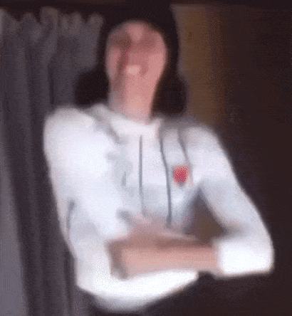 a blurry picture of a woman wearing a white shirt and a black hat dancing .