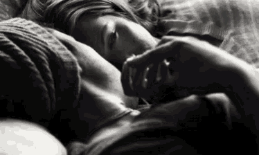 a black and white photo of a couple laying in bed .