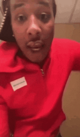 a man in a red hoodie is standing in a room .