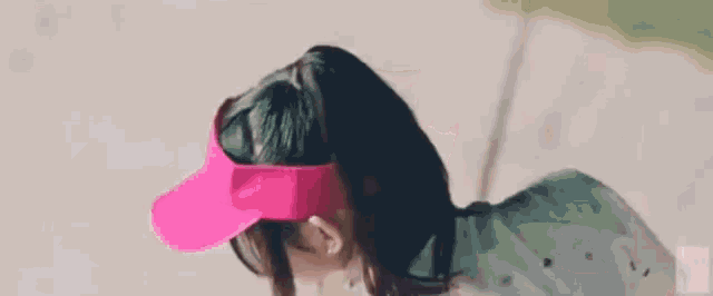 a woman wearing a pink hat and visor is looking at the camera .