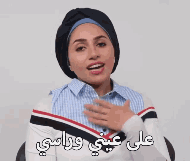 a woman wearing a turban and a white shirt with arabic writing on her chest