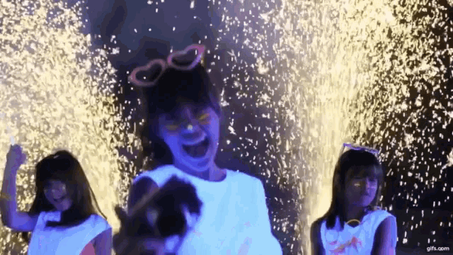 three girls are standing in front of a fireworks display