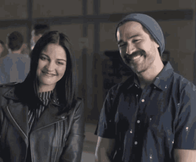 a man with a mustache is standing next to a woman with her arms crossed