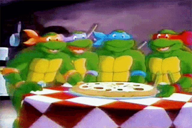 a group of teenage mutant ninja turtles are standing around a pizza on a table .