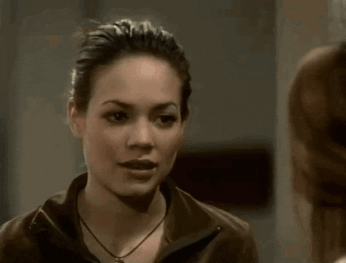 a woman in a white turtleneck is looking at a man in a dark room .