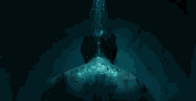 a man with a tattoo on his back is under a shower
