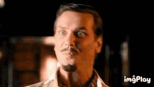 a man with a mustache is making a funny face .