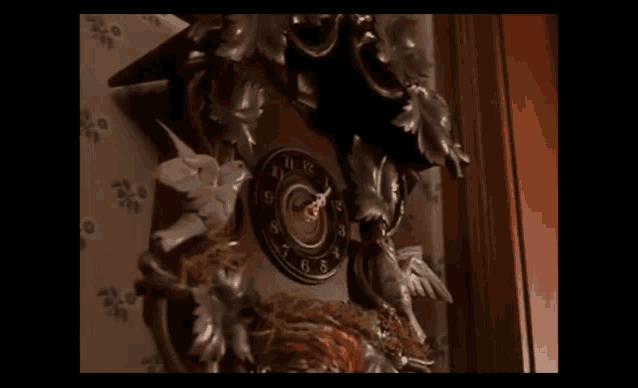 a cuckoo clock with birds and leaves on it shows that it is almost 5:00