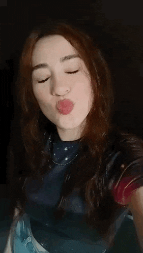 a woman with long red hair is taking a selfie with her phone .