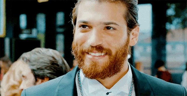 a man with a beard wearing a tuxedo and bow tie smiles