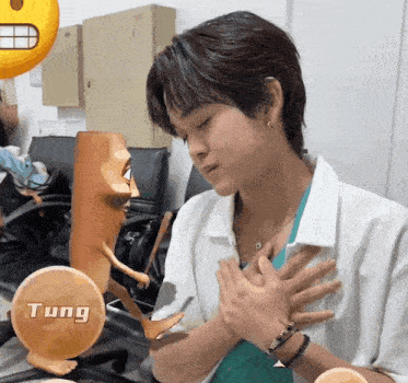 a person with their hands on their chest and a sticker that says tung behind them