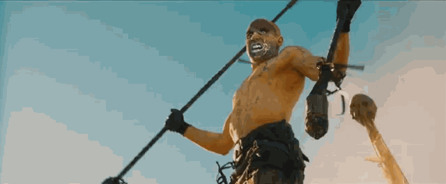 a man without a shirt is holding a spear in his right hand