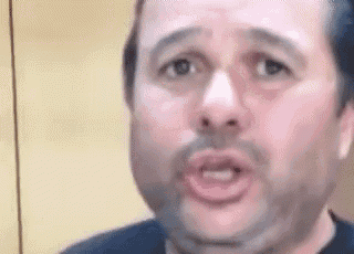a man with a beard is making a funny face and looking at the camera .