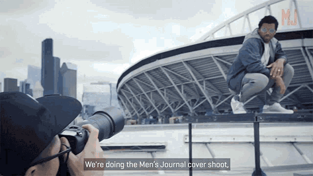 a man taking a picture of another man with the words we 're doing the men 's journal cover shoot below him