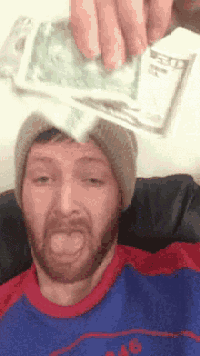 a man with a beard is holding a stack of twenty dollar bills on his head