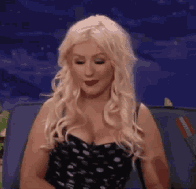 a woman with blonde hair and red lipstick is sitting on a couch