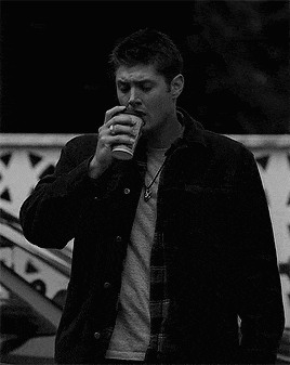 a man in a jacket is drinking from a cup .