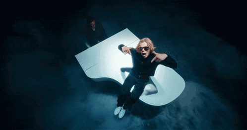 a woman is sitting on a white piano in a cloud of smoke