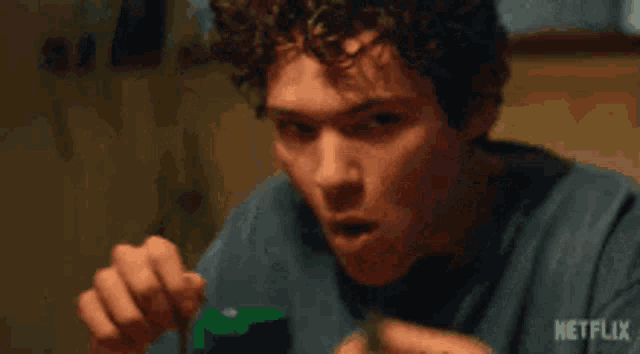 a man with curly hair is sitting at a table with a netflix logo in the corner