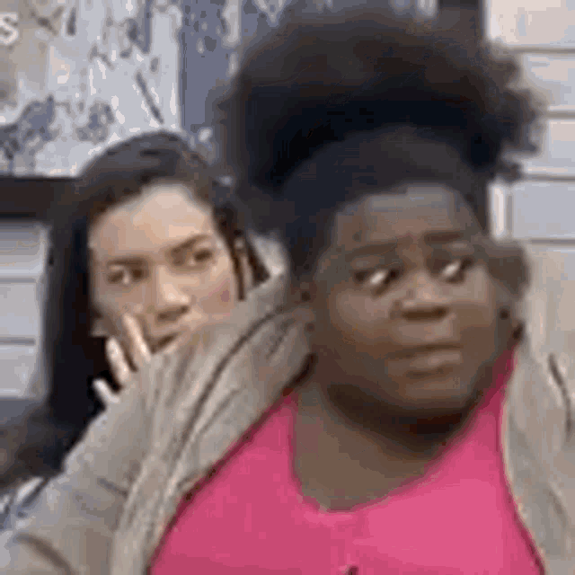 a woman in a pink shirt is sitting next to a woman in a tan jacket .
