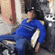 a man in a blue shirt and hat is sitting in a chair