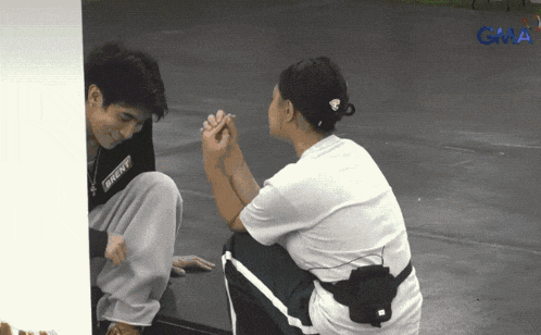 a man wearing a shirt that says bront sits next to a woman holding hands