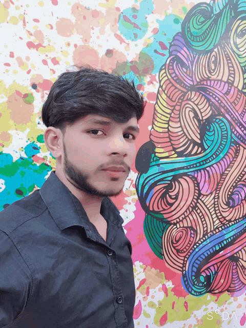 a young man stands in front of a colorful painting that says sdn