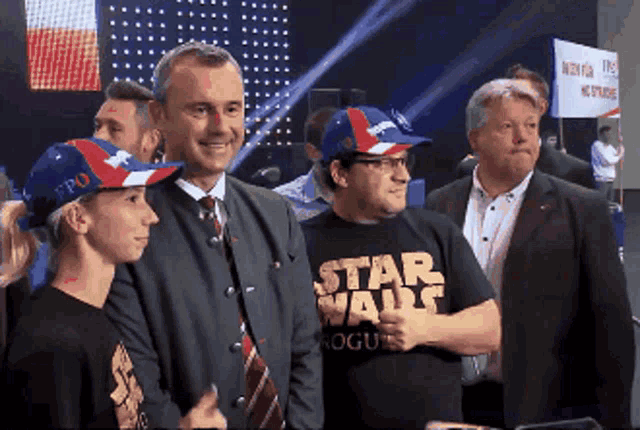 a man wearing a star wars shirt stands next to a man wearing a hat that says fpo
