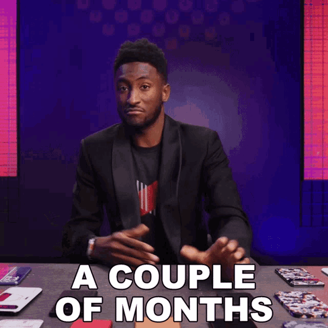 a man in a suit sitting at a table with a couple of months written on it