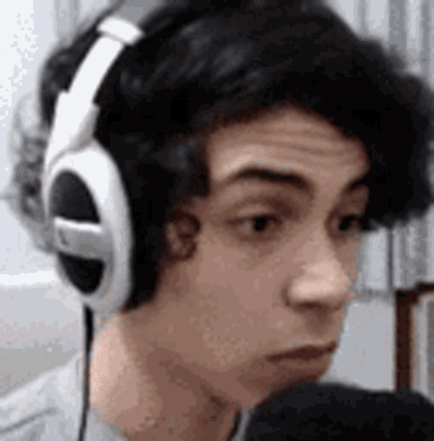 a young man wearing headphones and a microphone is looking at the camera .