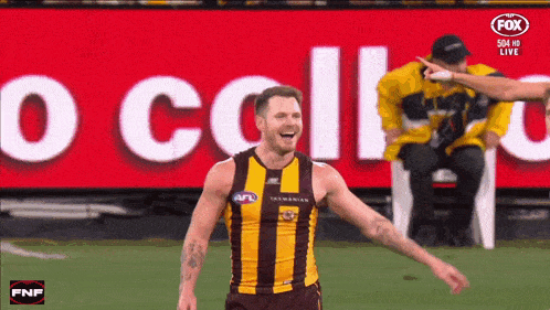 a man in an afl jersey is laughing in front of a fox advertisement