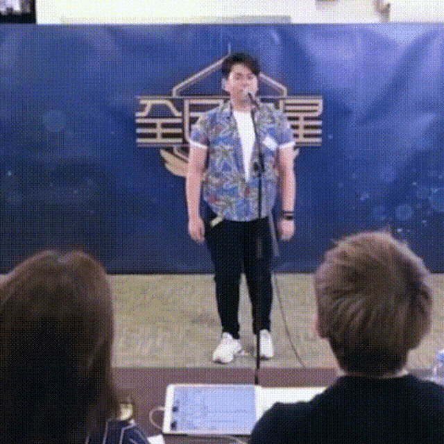 a man is standing in front of a microphone and singing into it .