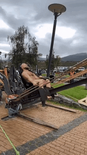 a man without a shirt is laying on a machine on a brick pavement .