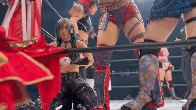 a woman is kneeling down in a wrestling ring with other women