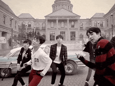 a group of young men are dancing in front of a large building that says ' canadian parliament building '