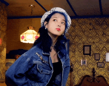 a woman with blue hair is wearing a denim jacket and a hat
