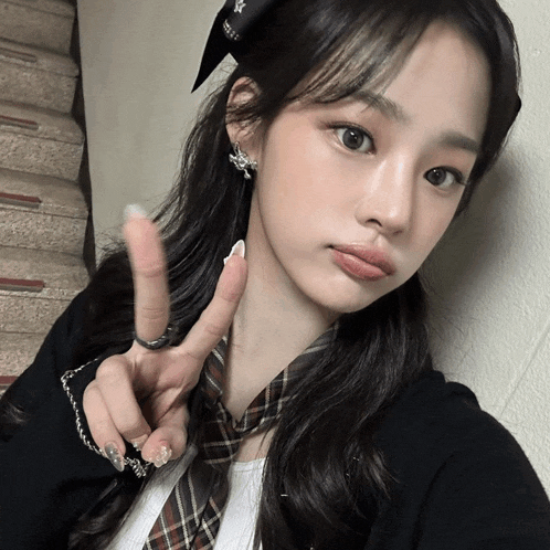 a girl wearing a headband and a tie is giving a peace sign