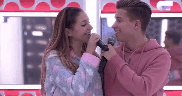 a man and a woman are singing into a microphone .