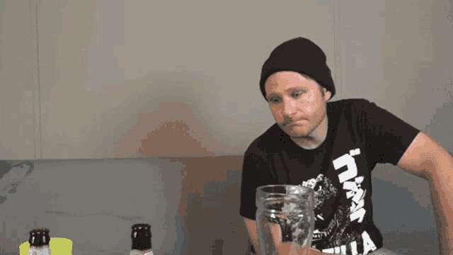 a man sitting on a couch wearing a shirt that says ' godzilla '