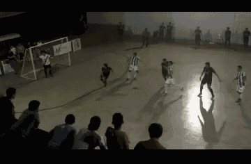 a group of people are watching a soccer game in a gym with a sign that says 44 on it