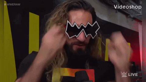 a man with long hair and a beard is wearing a pair of sunglasses that look like a batman mask .