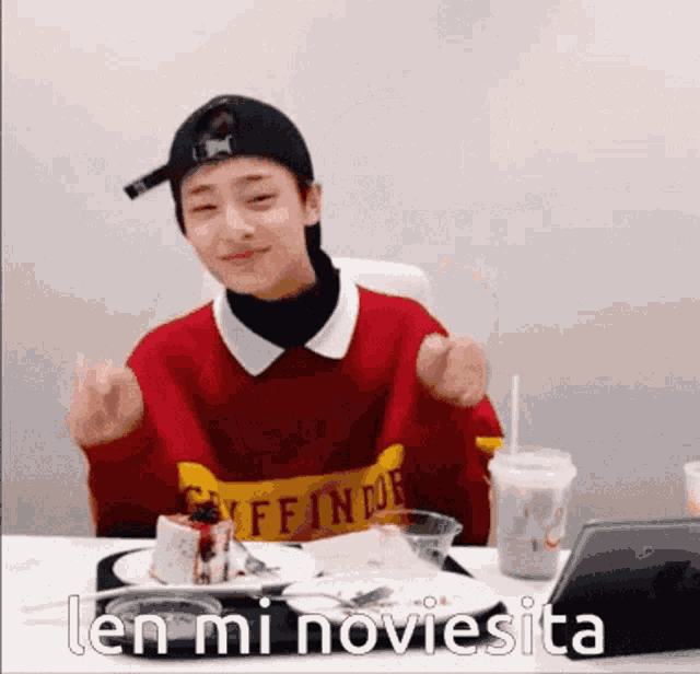 a boy wearing a red sweater that says gryffindor sits at a table